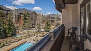 Ein Balkon mit Pool, Liegestühlen und Blick auf ein Wohngebiet mit Bäumen und Häusern.