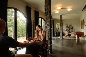 A dining area with a large window, stone pillars, and a view of the outdoors. - The Cave, at Dahlonega Estate (Dahlonega)