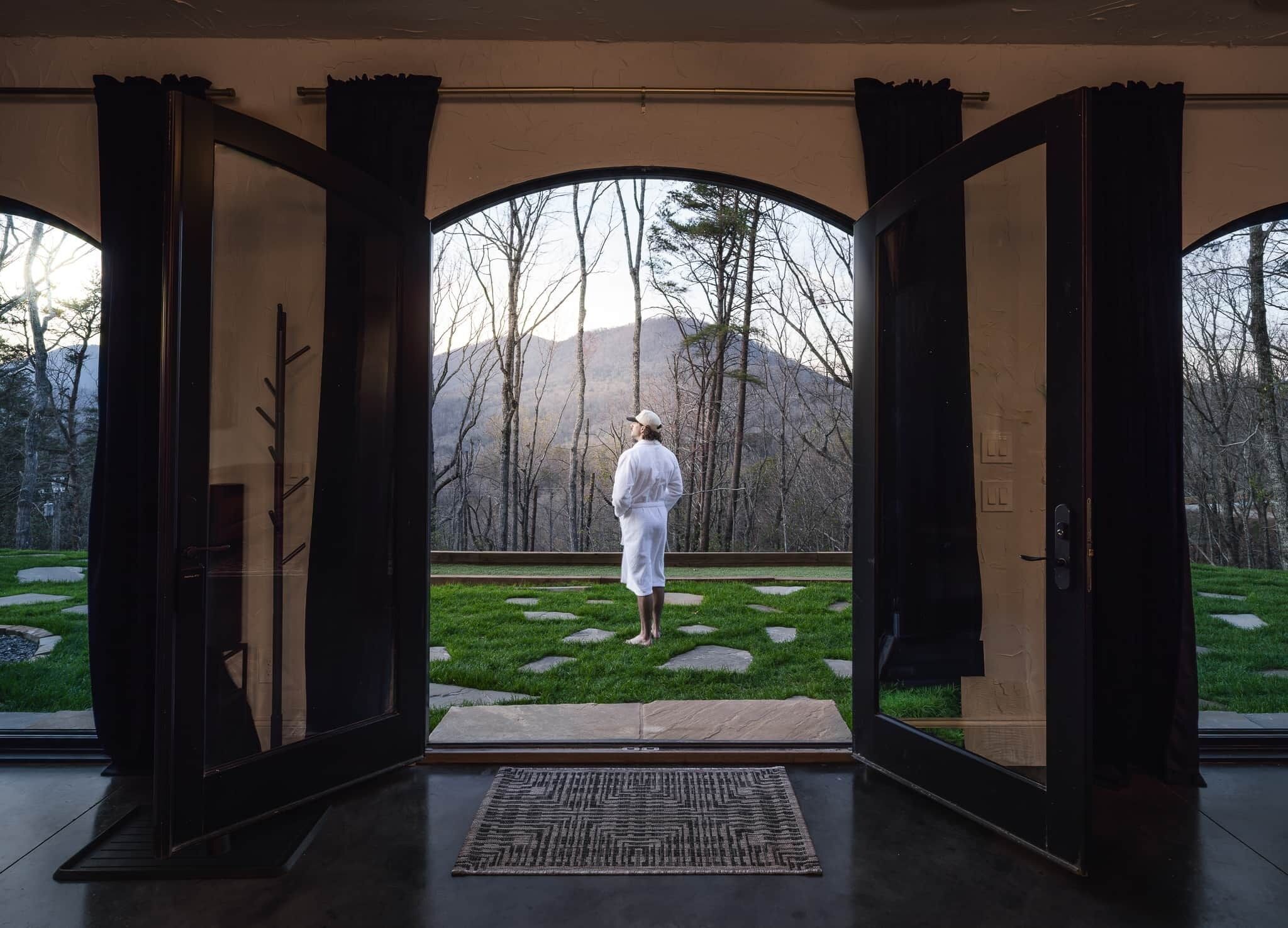 A room with large glass doors leading to an outdoor garden with a stone pathway and trees.