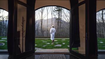 A room with large glass doors leading to an outdoor garden with a stone pathway and trees.