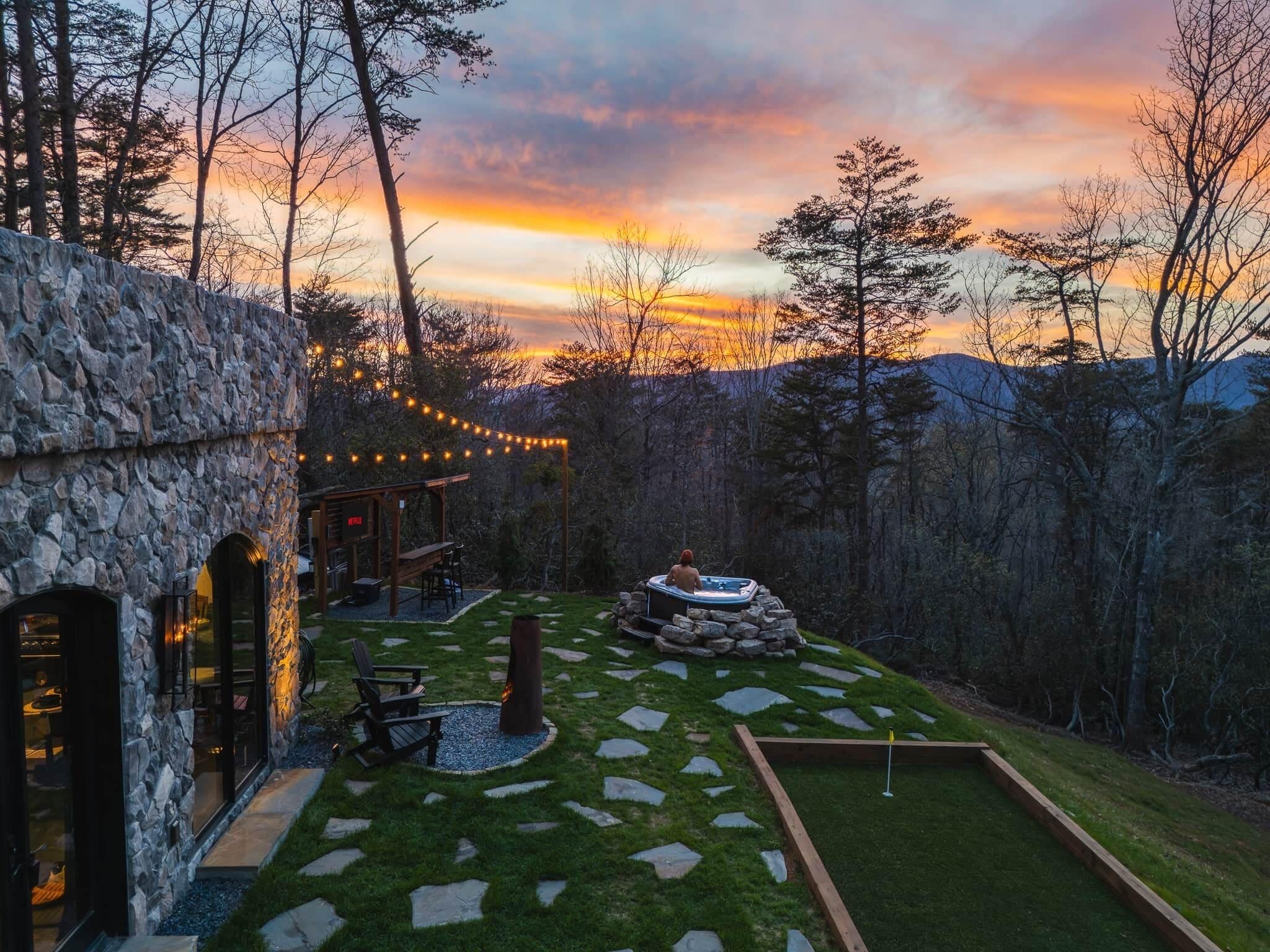 A stone building with a hot tub, outdoor seating, and a stone pathway.