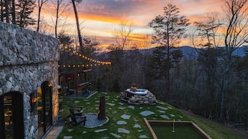 A stone building with a hot tub, outdoor seating, and a stone pathway.