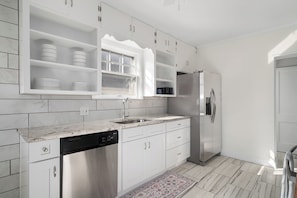 A modern kitchen with white cabinetry, a stainless steel refrigerator, and a dishwasher. - Adorable Westwood house newly updated, great central location! World Cup ready! (Kansas City)