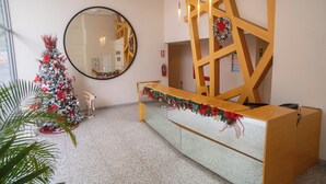 En receptionsdisk med en spegel, en julgran och en trävägg som avskärmning.