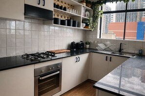 A modern kitchen with a gas stove, oven, and a window with a city view. - Stylish 1BDR Redfern Retreat Walk to CBD Station (Redfern)