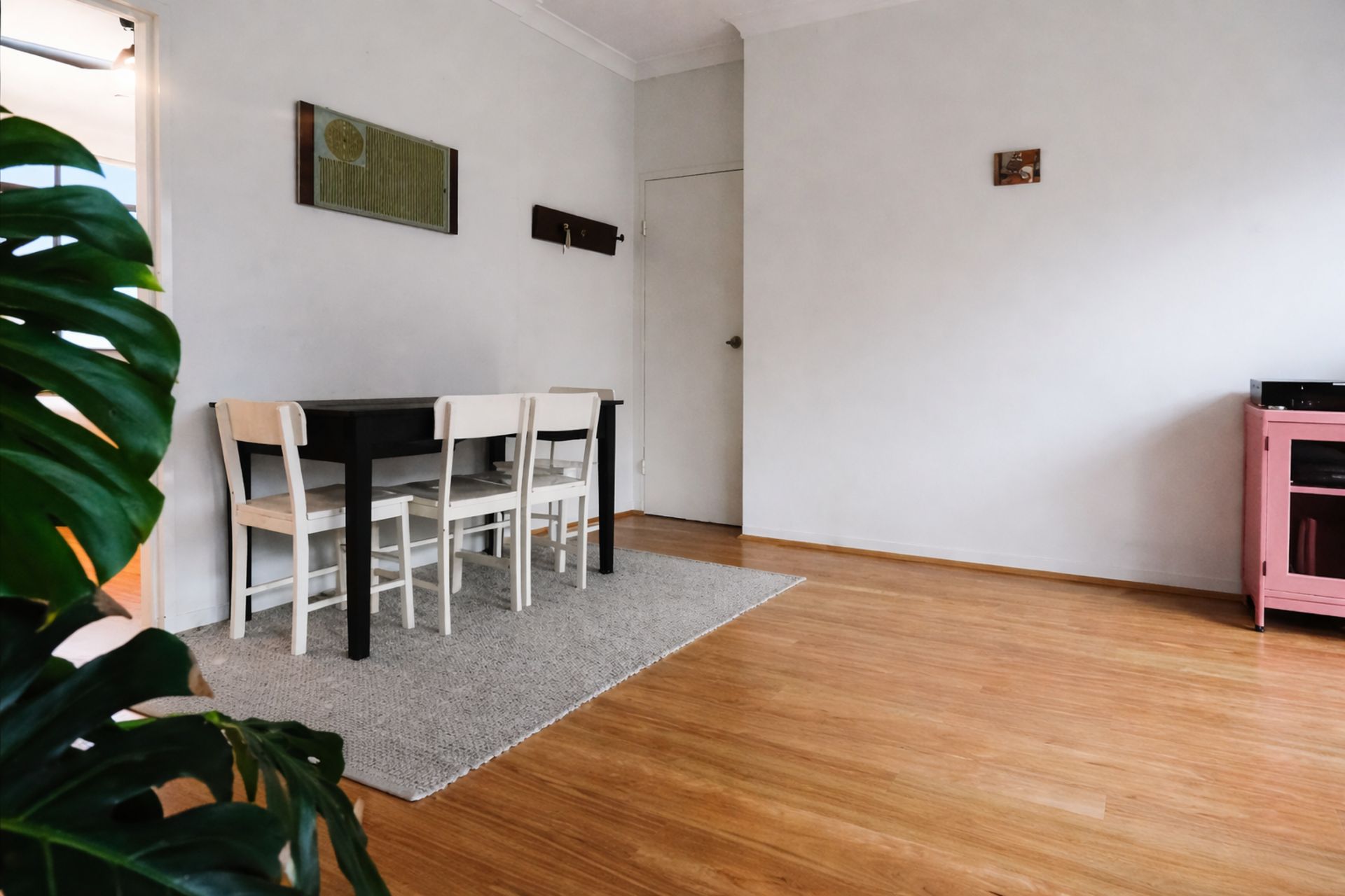 Une pièce comprenant une table à manger et des chaises, un tapis gris et un meuble rose.