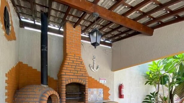 A brick-built outdoor kitchen with a chimney, a counter, and a potted plant. - Pousada Pérola do Mar (Tamandaré)