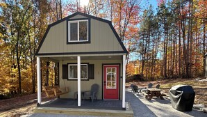 A small, single-story building with a red door and a covered porch area.