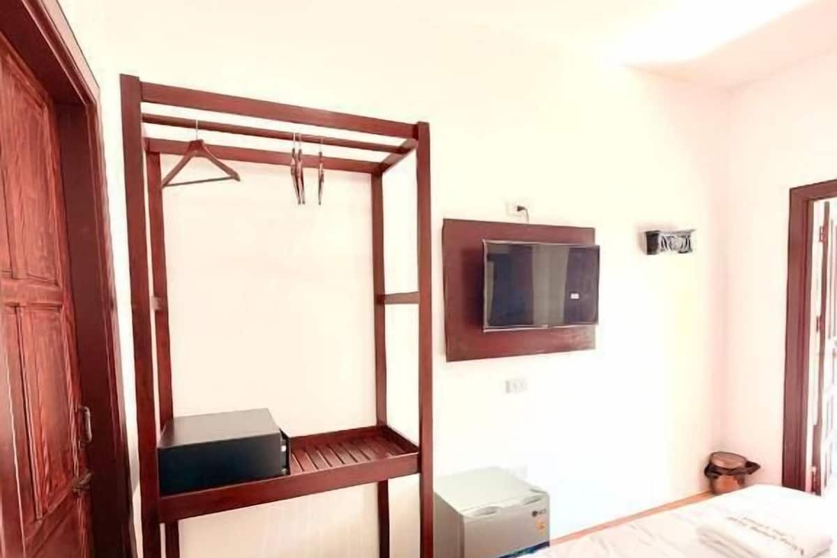 A room with a bunk bed, a television, a small desk, and a trash bin.