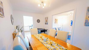 A dining area with a long wooden table, chairs, and a dartboard.