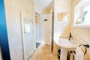 Un baño con lavamanos blanco, un perchero y una puerta con la inscripción 'Bathroom'.