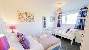 A bedroom with a bed, bedside table, lamp, and artwork on the wall.