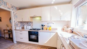 A kitchen with white cabinets, a stove, a sink, and a window.