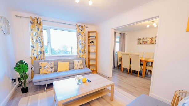 A living room with a sofa, coffee table, and a dining area with chairs and a table.