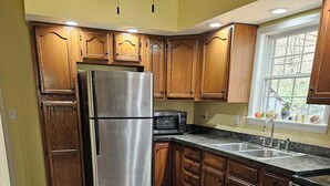 Una cocina con armarios de madera, un refrigerador de acero inoxidable, un microondas y un fregadero.
