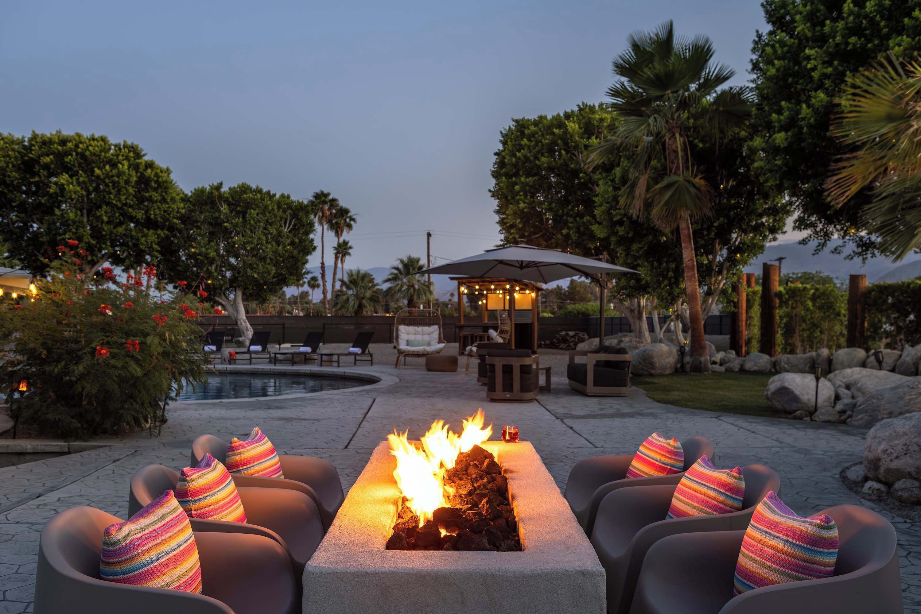 A fire pit with seating, a pool, and outdoor furniture.