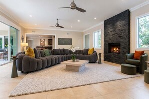 A modern living room with a sectional sofa, a fireplace, and a dining area. - Mockingbird by Nest Villas | Mid Century Estate (Indian Wells)