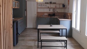 A modern kitchen with a dining area, wooden accents, and pendant lighting.