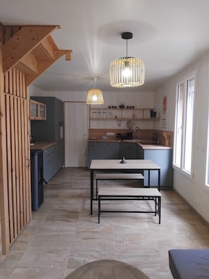 Una cocina moderna con comedor, detalles de madera e iluminación colgante.