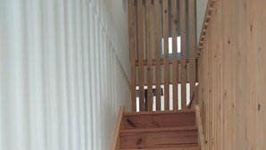 A wooden staircase with a metal handrail, leading to a higher floor.