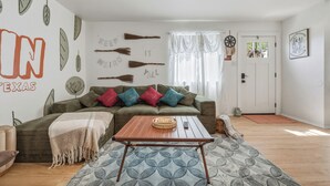 En stue med sofa, sofabord og en væg med pynt.