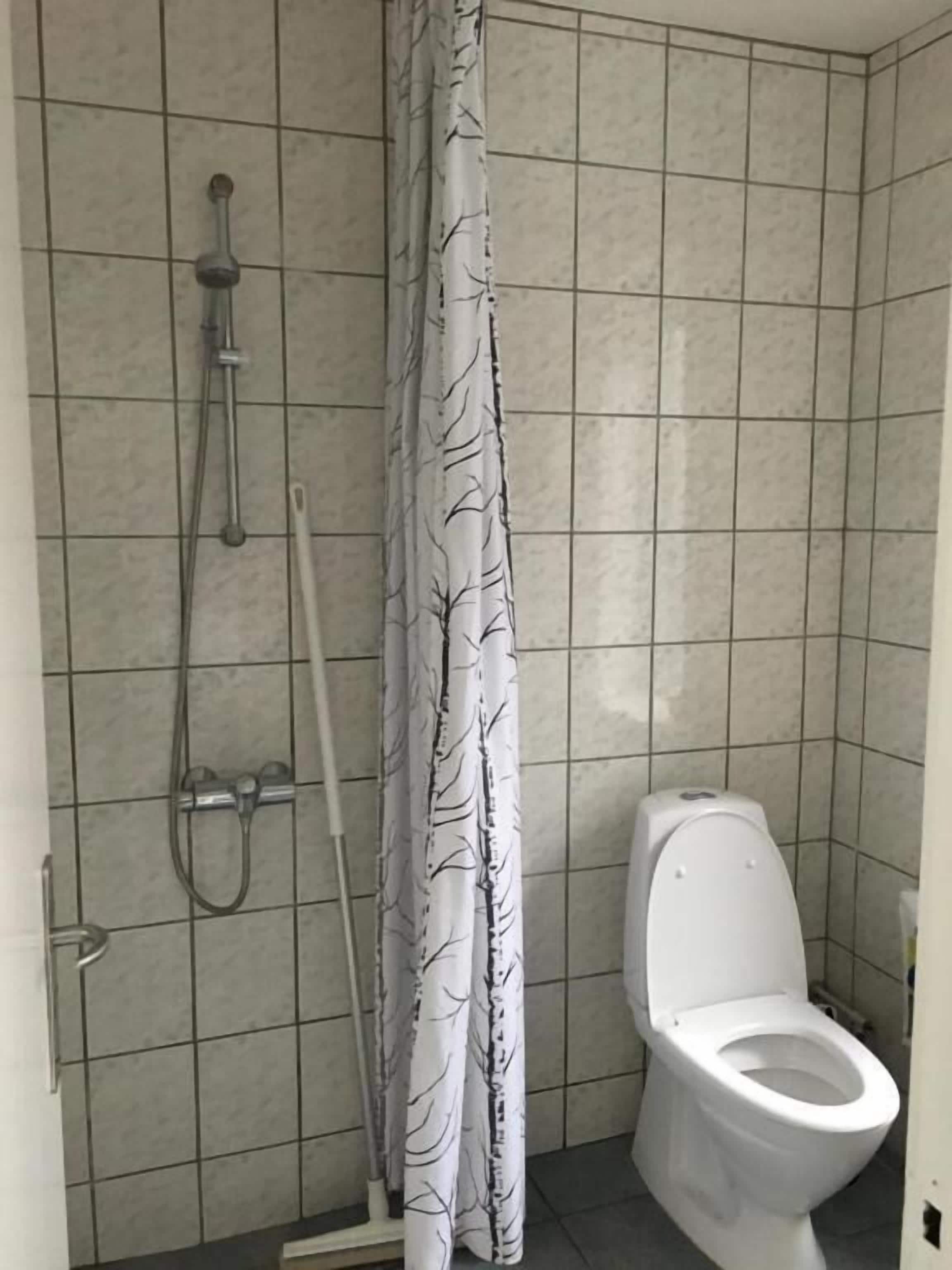 A bathroom with a shower, toilet, and a curtain with a tree pattern.