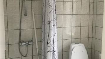 A bathroom with a shower, toilet, and a curtain with a tree pattern.