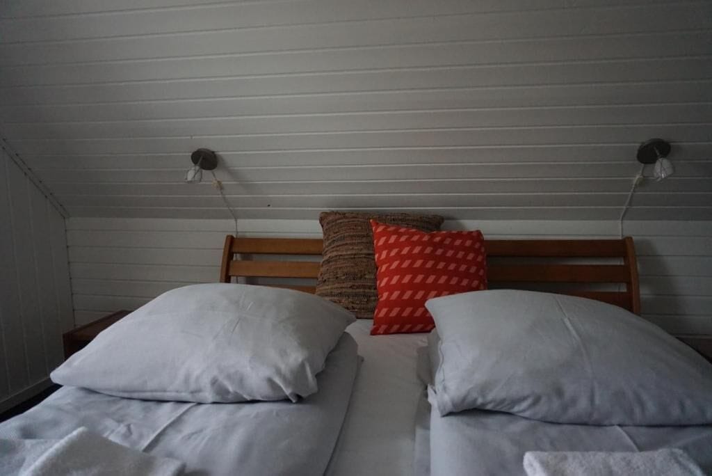 Una habitación con dos camas individuales, un cabecero de madera y dos lámparas fijadas a la pared.