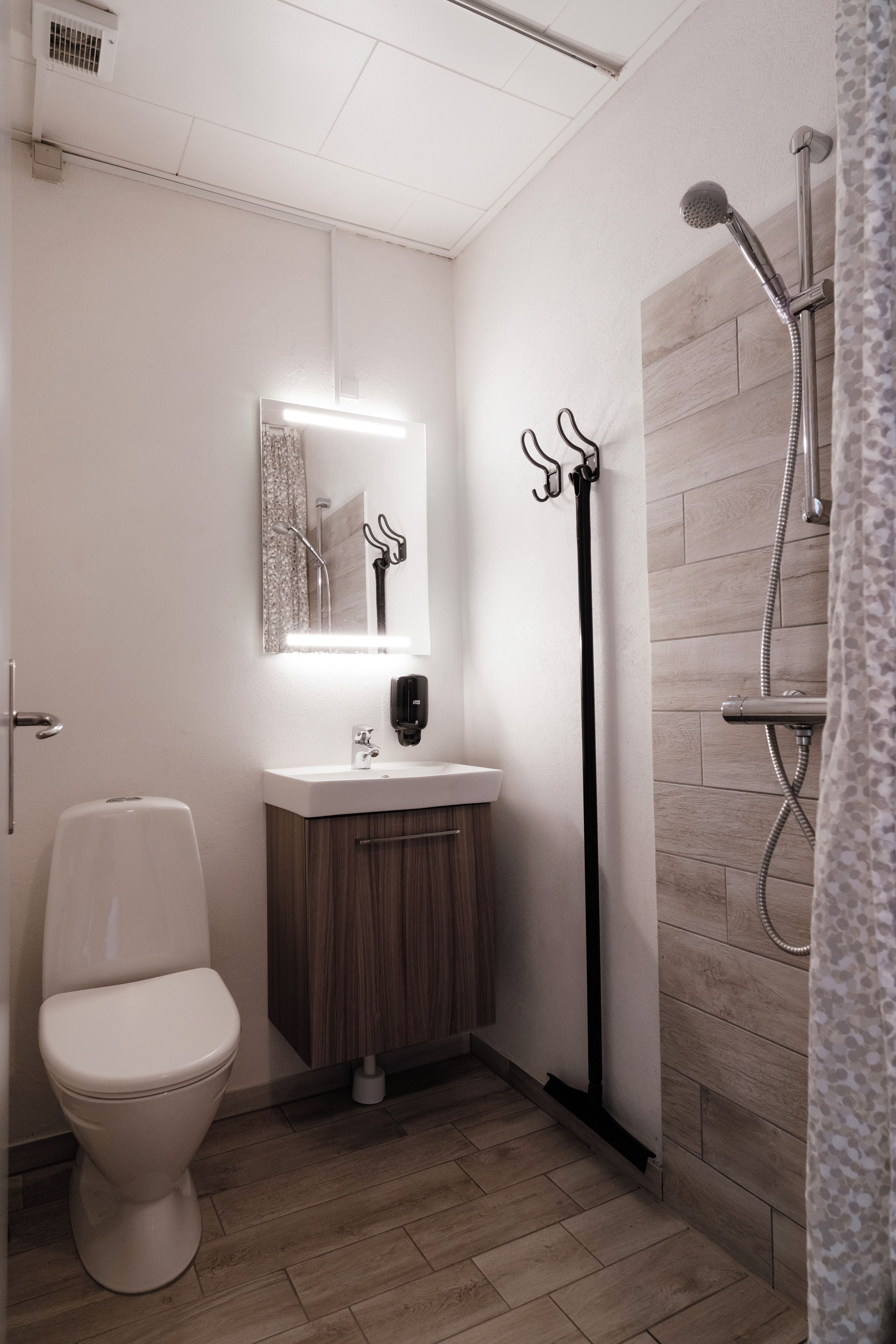 Un baño con inodoro, lavabo, espejo y ducha.