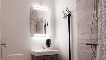 Un baño con inodoro, lavabo, espejo y ducha.