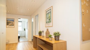 A hallway with wooden flooring, a wooden console table with potted plants, and framed pictures on the walls. - B&B by the Sea Hirtshals (Hirtshals)