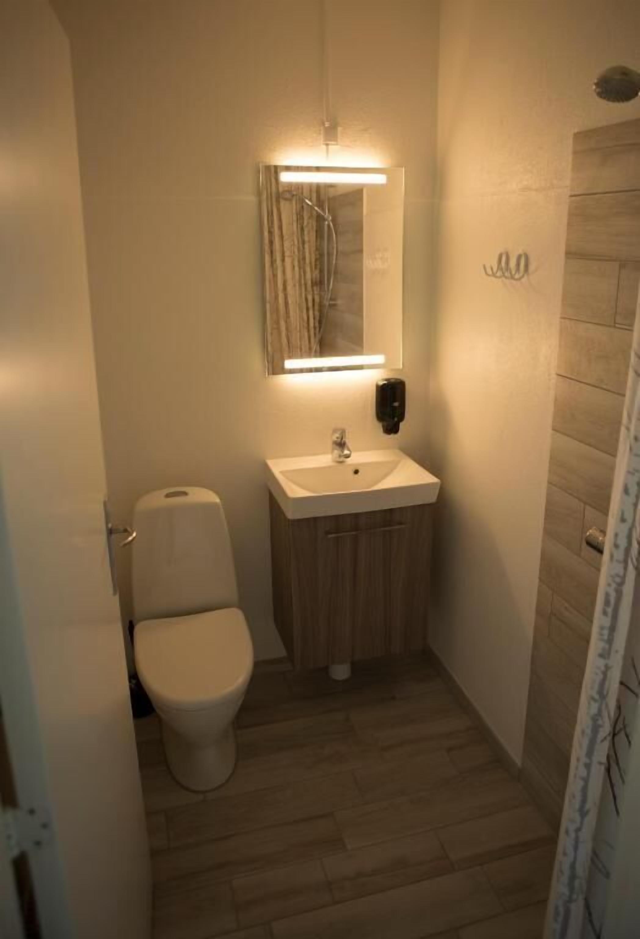 A small, compact bathroom with a toilet, sink, and mirror.
