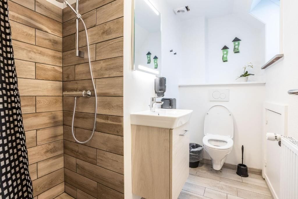 Une salle de bain équipée d’une douche, de toilettes, d’un lavabo et d’un miroir.