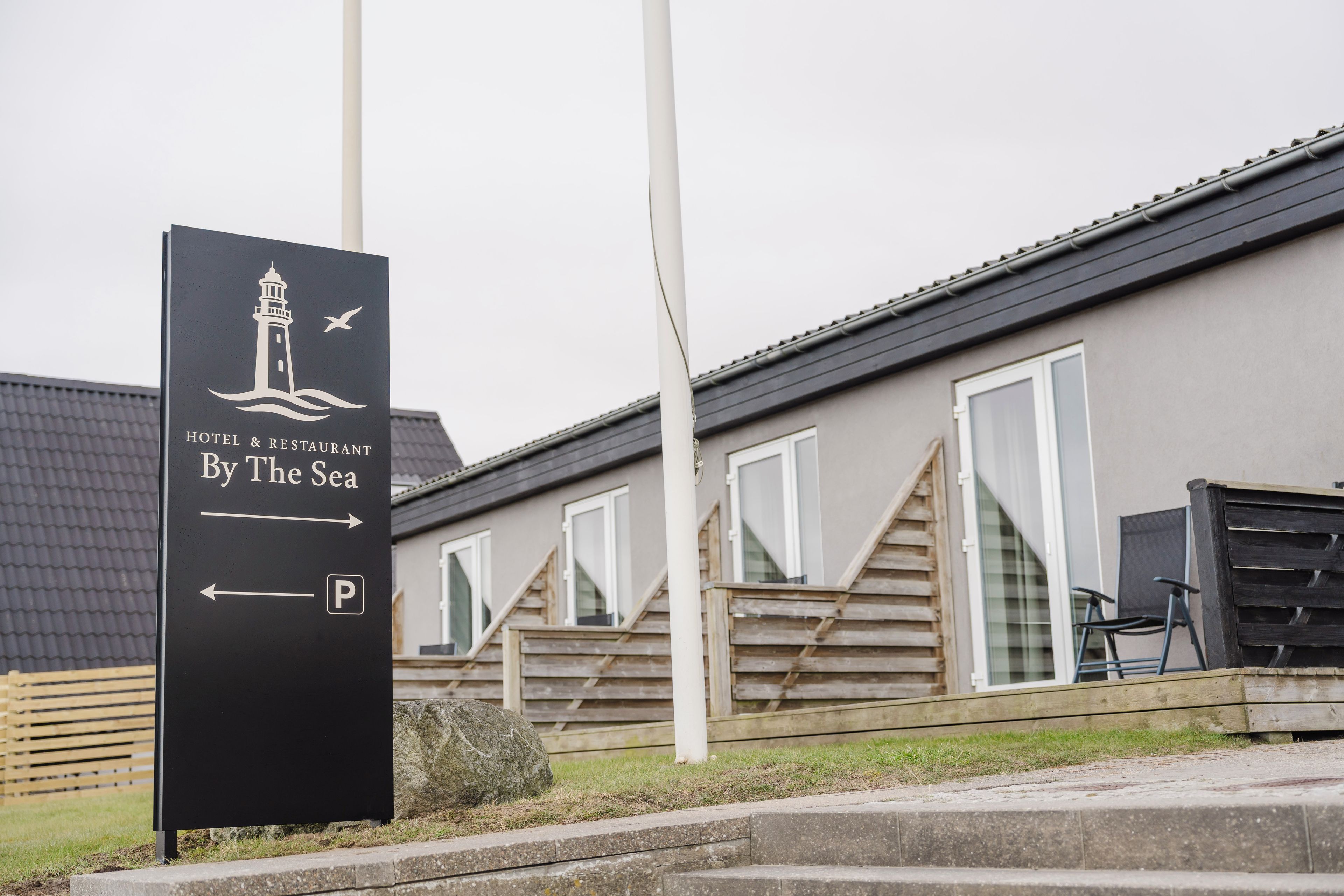 A sign for a hotel and restaurant by the sea, with a parking direction indicated.