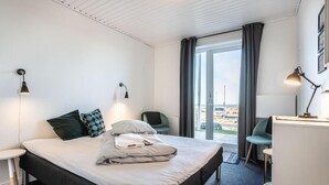 Habitación de hotel con cama, dos mesitas de noche, un escritorio, una silla y vistas al exterior.