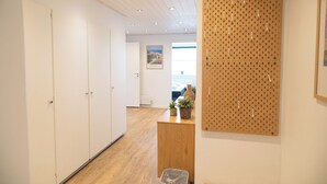 Un pasillo con suelo de madera, un mostrador de recepción de madera, una corcho y un cuadro en la pared.