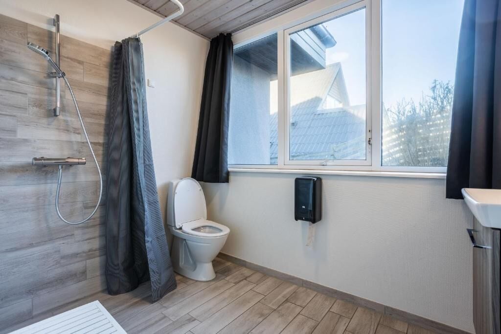 Un baño con ducha, inodoro y ventana.