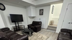 A living room with a sofa, a coffee table, a TV, and a cabinet. - Stylish, conducive, and serene 2-bedroom suite located in the heart of Brighton, (Saskatoon)