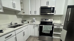 A modern kitchen with white cabinets, stainless steel appliances, and a wooden floor. - Stylish, conducive, and serene 2-bedroom suite located in the heart of Brighton, (Saskatoon)