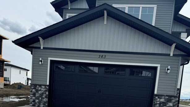 A modern two-story house with a garage, numbered 143, and a paved driveway. - Stylish, conducive, and serene 2-bedroom suite located in the heart of Brighton, (Saskatoon)