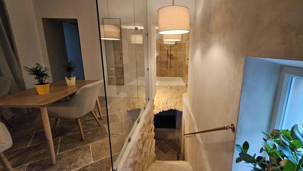 Une salle de bain moderne avec une douche, un escalier à ossature de verre et un coin repas comprenant une table et des chaises.