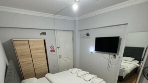 A hotel room with a bed, a wardrobe, a television, and a mirror. - Filyos Lotus Pansiyon (Caycuma)