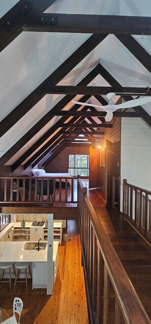 Een loft-achtige kamer met een keukenhoek, houten balken en een trap.