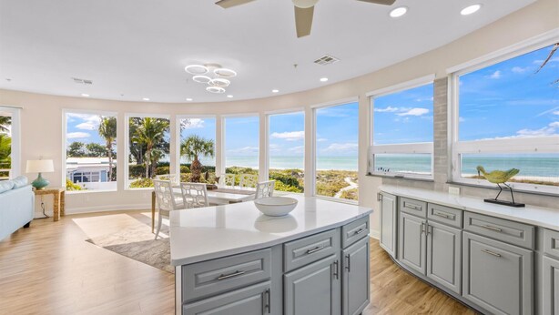 Una cocina moderna con ventanas amplias, una isla central y vista al mar.