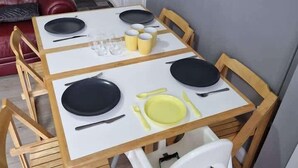 Ein Esstisch mit vier Stühlen, einer weißen Tischdecke sowie Tellern, Tassen und Besteck.