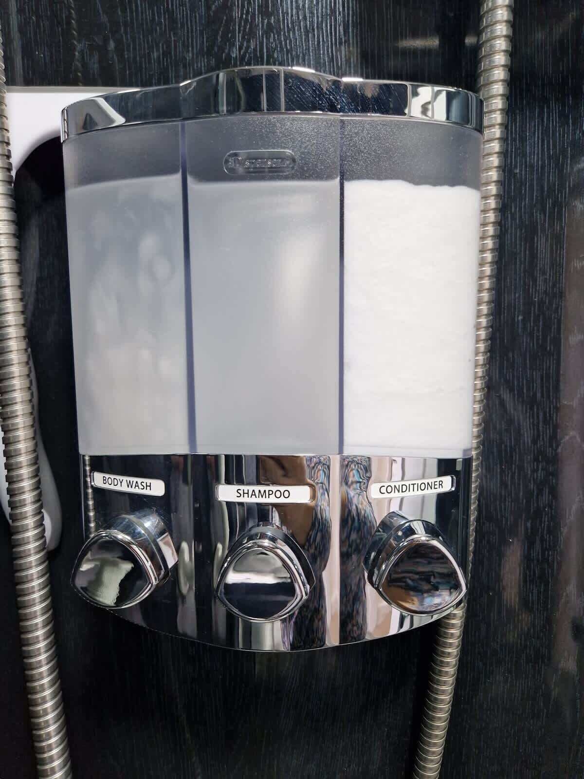 Eine chrombeschichtete Duschsteuerung mit drei Wasserhähnen, beschriftet mit 'KÖRPERWÄSCHE', 'SHAMPOO' und 'SPÜLUNG'.