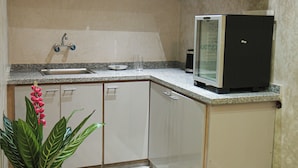 A compact kitchen with white cabinets, a built-in refrigerator, a sink, and a potted plant. - Dar Medina (Marrakech)