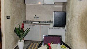 A compact kitchen with cabinets, a television, and a dining area with a table and chairs. - Dar Medina (Marrakech)