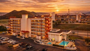 A hotel with multiple floors, a swimming pool, and a parking lot.