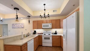A kitchen with wooden cabinets, a white refrigerator, a microwave, a stove, and a chandelier.